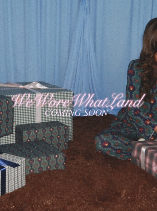 Danielle Bernstein in navy pajamas standing next to a decorated Christmas tree with 'We Wore What Land' text overlay.